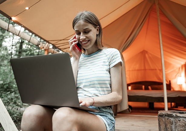 junge Frau surft und telefoniert beim Camping