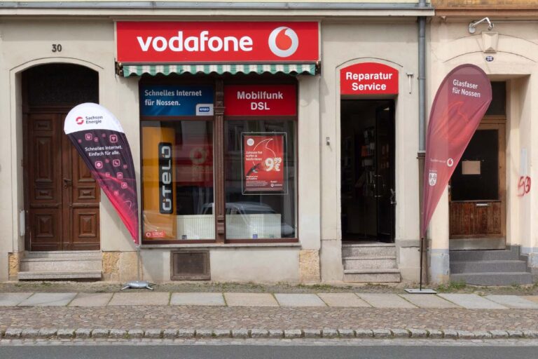 Dein Vodafone-Shop in Nossen mit rotem Eingangsbereich und Info-Flaggen vor dem Schaufenster.